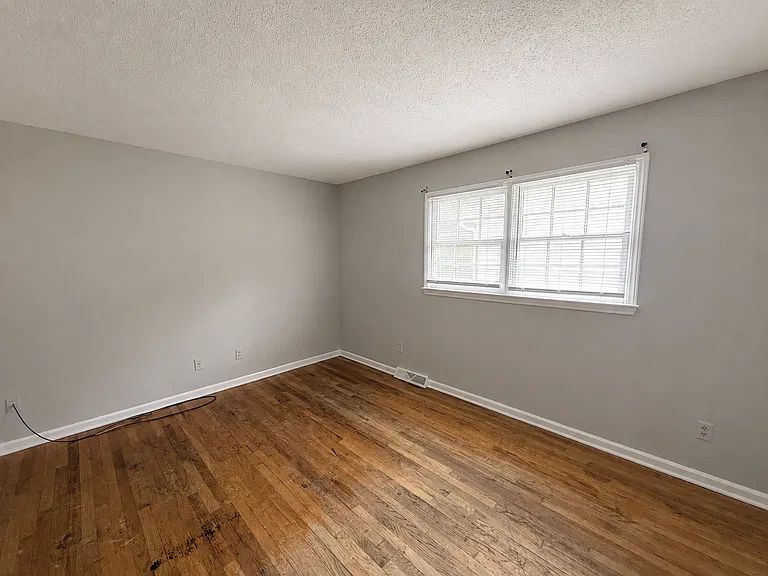 Bedroom with a wide window and wood flooring