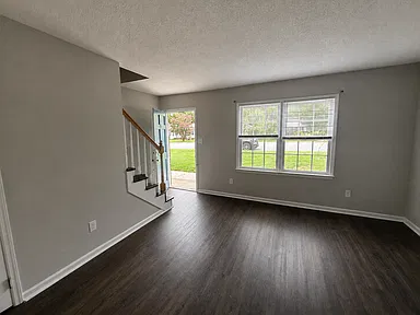 Living area with hard-surface flooring, front window, and stairs