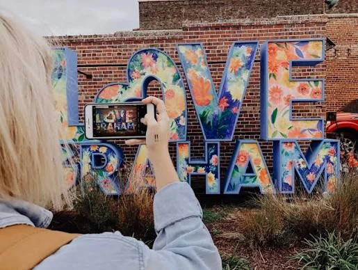 A visitor photographing colorful Love Graham public art